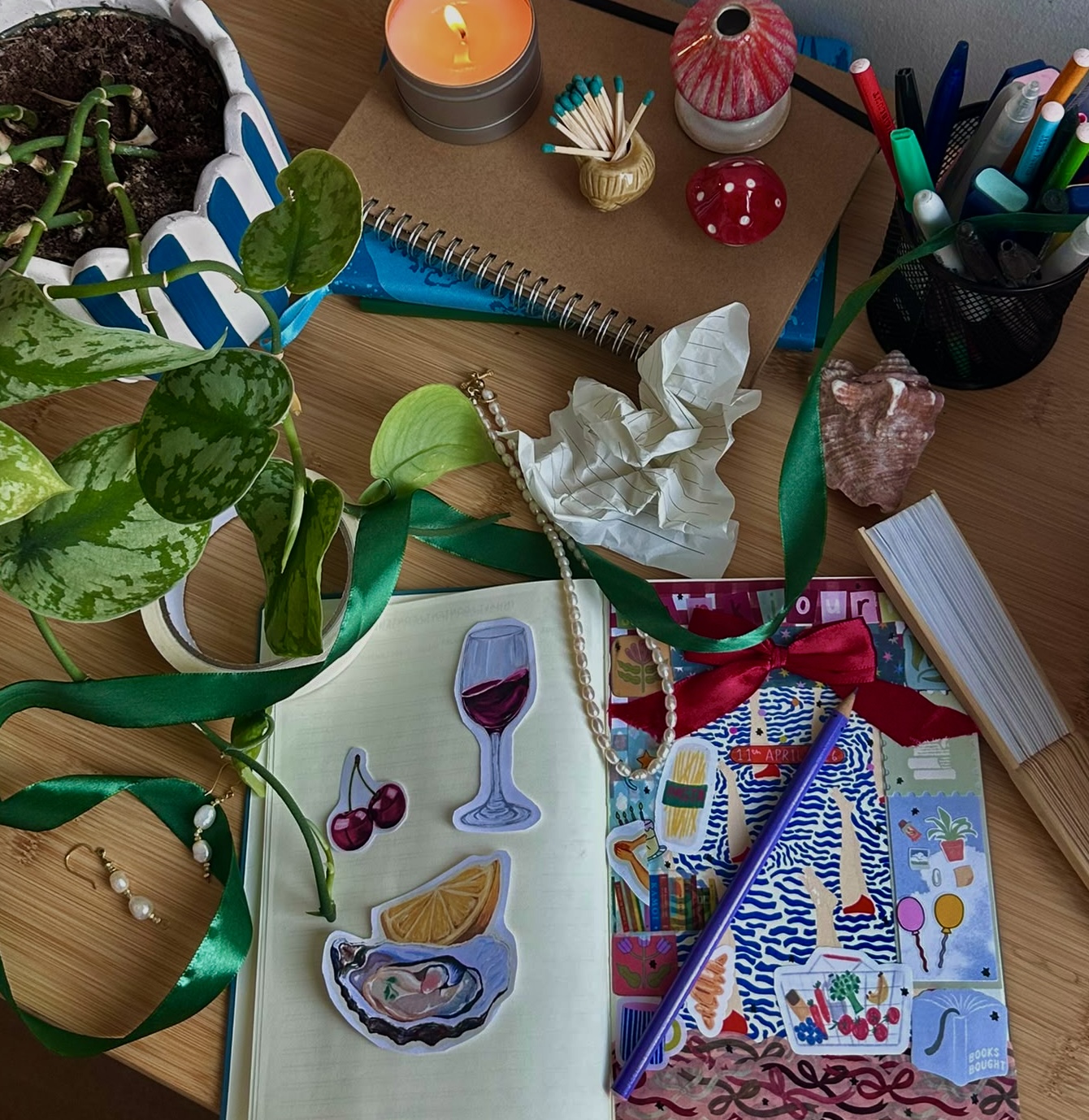 A scrapbook page with wine and cherry illustrations surrounded by plants, pens and paper