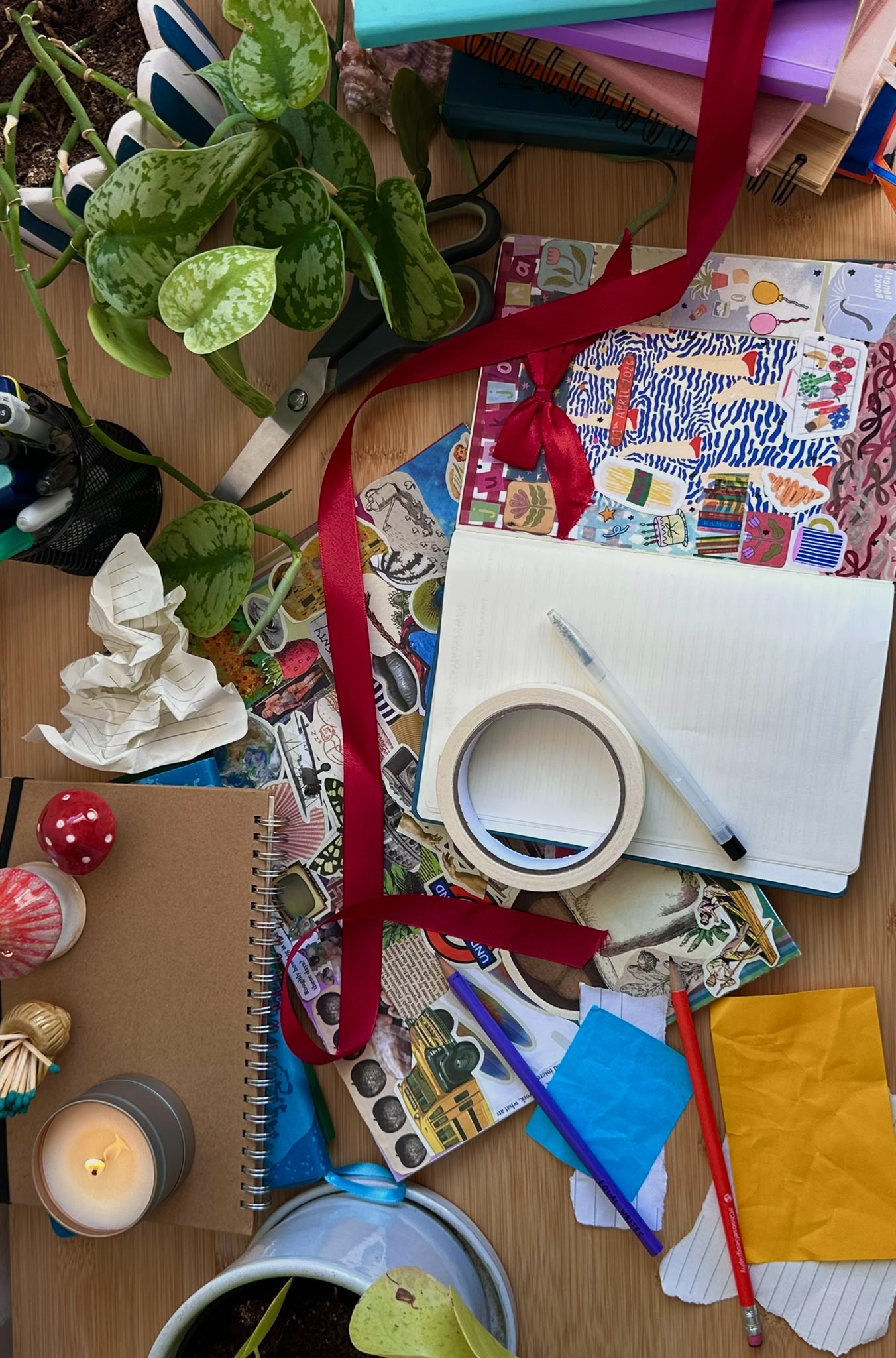 Scrapbooking materials, journals, paper and ribbons arranged across a creative workspace