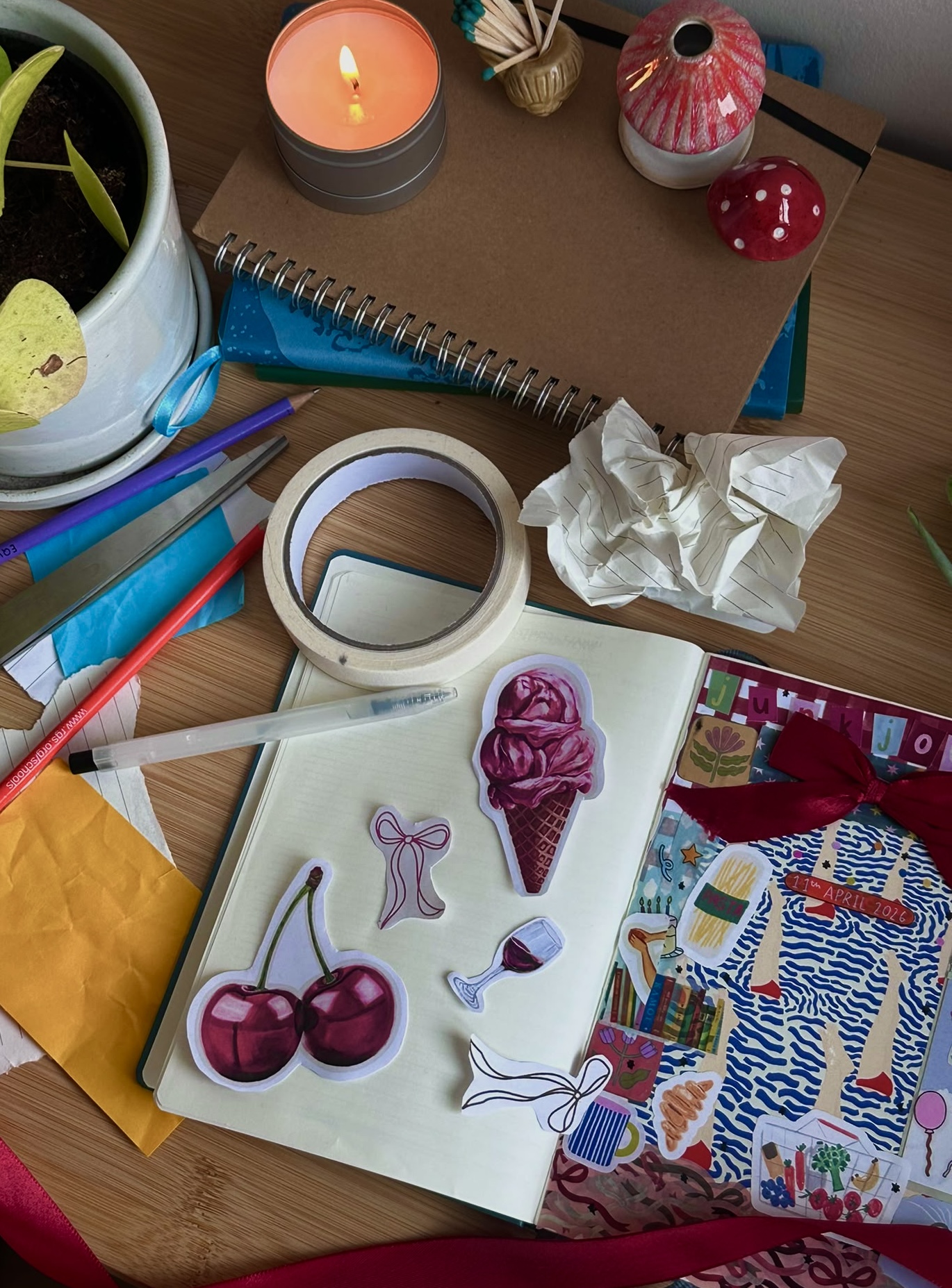 An open scrapbook beside scissors, paper pieces and colourful creative materials